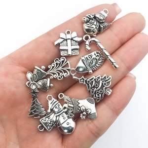 Detalle de colgantes navideños en plata antigua con diseños de muñeco de nieve y copos