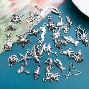 Macro shot of silver-plated ocean charms including sea turtles and shells for DIY jewelry