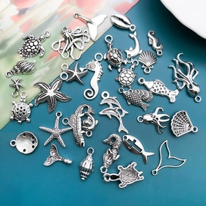 Macro detail of assorted antique silver ocean charms including turtles, seahorses and shells
