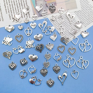 Detailed collection of silver alloy heart charms for DIY jewelry making on blue background