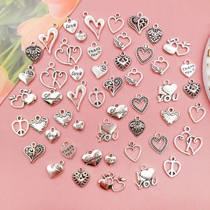 Macro shot of assorted antique silver heart charms with engraved love messages on pink background