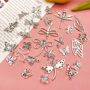 Detailed flat lay of vintage silver insect charms for DIY jewelry on pink background