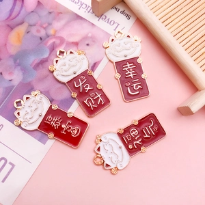 Détail de breloques Maneki Neko en émail rouge et blanc avec base dorée et messages de chance