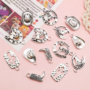 Flat lay of vintage silver western charms featuring cowboy hats, boots and cactus on pink