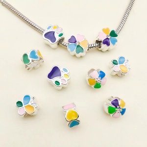 Detail of silver DIY enamel beads featuring flower, cat paw and butterfly designs