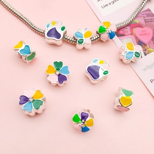 Macro shot of colorful enamel charms featuring cat paws, flowers, and butterfly designs