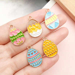 Five colorful enamel Easter egg pendants with cute bunny and chick patterns held in hand
