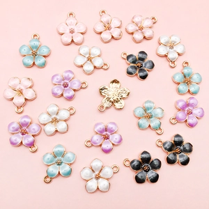 Flat lay detail of assorted colorful enamel flower charms with gold-plated DIY loops