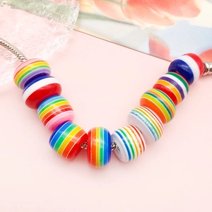 Makroaufnahme bunter Regenbogenstreifen-Resinperlen auf einem silbernen Schlangenarmband