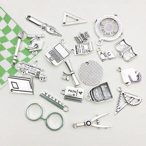 Macro view of vintage silver alloy school charms featuring caps and stationery