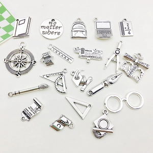 Macro detail of vintage silver graduation charms including diploma and mortarboard icons