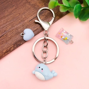 Blue whale resin keychain with heart and sweet candy pendants on wood background