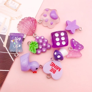 Close-up of purple and pink resin pendants featuring shells, cat paws, and stars with glitter