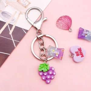 Purple grape and candy keychain with silver ring on aesthetic pink background