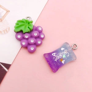 Detailed macro view of purple resin charms including grape and candy bag with sweet text