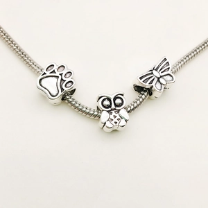 Silver snake chain bracelet featuring owl, butterfly and paw print charms in antique finish