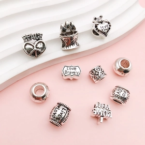 Detailed view of vintage silver DIY charms with heart and bear shapes featuring engraved words