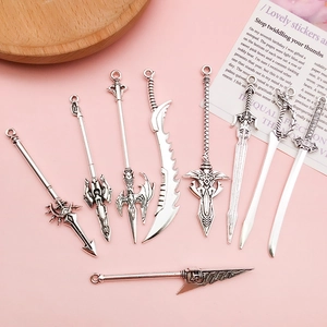 Détail de huit pendentifs épées fantaisie en alliage argenté vintage sur fond rose doux