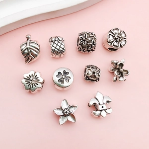 Macro detail of various alloy large hole beads featuring floral and star shapes for DIY bracelets