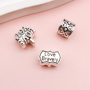 Detailed view of vintage silver alloy charms with Love Bravely text and heart patterns