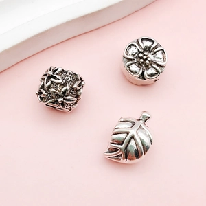 Macro shot of antique silver alloy beads with hollow flower, cherry blossom, and leaf charms