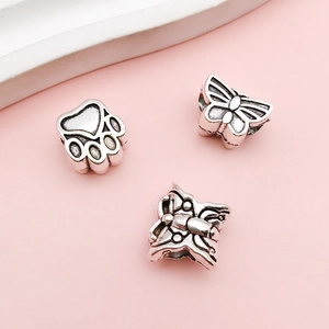 Detailed view of vintage silver alloy cat paw and butterfly charms for DIY bracelets