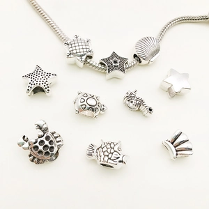 Gros plan de breloques tortue et vie marine en argent sur un bracelet chaîne serpent DIY