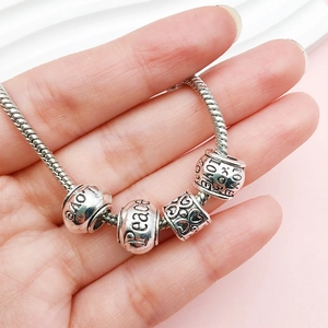 Detail of silver alloy charm bracelet with LOVE and Peace beads on snake chain