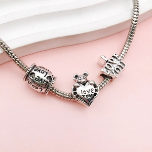 Detailed macro view of silver snake chain bracelet featuring heart charm and love beads