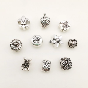 Detail of vintage silver alloy charms featuring floral and clover motifs for DIY bracelets