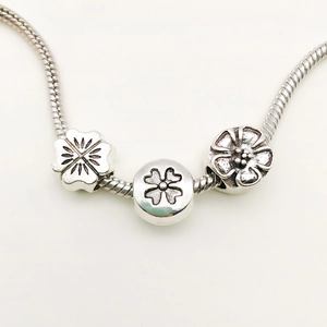 Silver vintage snake chain bracelet featuring floral and four-leaf clover charms