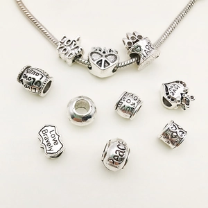 Macro shot of silver alloy charm beads with LOVE YOU and HAPPY engravings for DIY jewelry