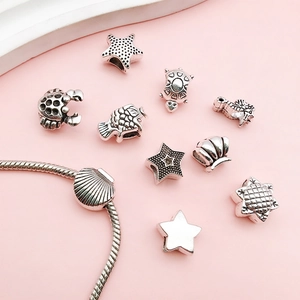 Gros plan de charms en argent vintage avec étoile de mer et tortue sur un bracelet serpent