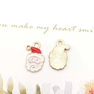 Detail of enamel Santa Claus charm showing red hat, white beard and golden metal back
