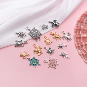 Collection of turtle-shaped jewelry pendants in gold and silver finishes on silk fabric