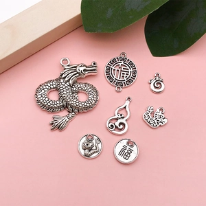 Macro view of vintage silver dragon and gourd charms for DIY jewelry making
