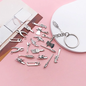 Flache Darstellung von Vintage-Miniatur-Werkzeuganhängern aus Silberlegierung auf Rosa