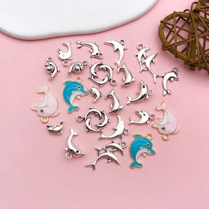 Flat lay of small dolphin charms in blue and pink enamel for DIY jewelry making