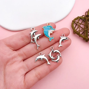 Set of dolphin charms for jewelry making held in hand for size visualization