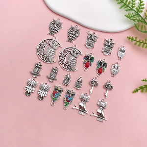 Flat lay of vintage owl and key alloy pendants for DIY jewelry making on pink background