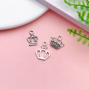Set of three vintage silver crown pendants for DIY necklaces and bracelets on pink background