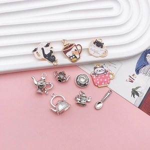 Macro shot of cute enamel cat in teacup charm and silver teapot alloy DIY jewelry set