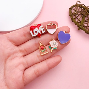 Detailed view of hand-held enamel heart charms and crystal rose pendants for DIY jewelry