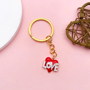 Golden heart pendant with red enamel LOVE lettering on a pink aesthetic background