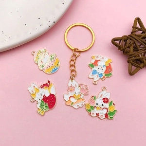 Gros plan de jolis charms lapin en émail et porte-clés à motifs floraux sur fond rose