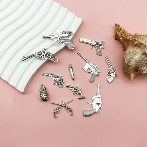 Detailed view of vintage silver alloy gun and bullet charms for DIY jewelry making