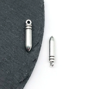 Macro shot of silver bullet-shaped alloy charms with grooved details and hanging loops