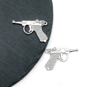 Detail shot of vintage silver-tone Luger pistol charm for DIY jewelry on stone base