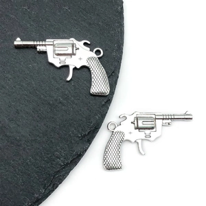Detailed close-up of silver-tone alloy revolver charms with textured grips for DIY jewelry