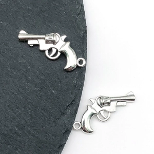 Close-up of two miniature silver alloy revolver pendants with detailed metallic finish
